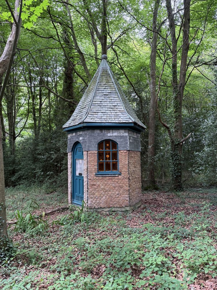 A small brick tower with a slate roof in the woods